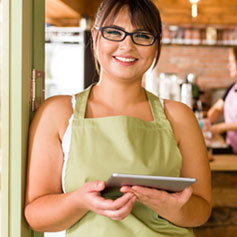 Cafe owner stands in doorway holding tablet